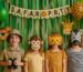 Vier Kinder bei einer Safari-Party mit Tiermasken vor grüner Dschungel-Deko – perfekte Motto-Feier für Kindergeburtstag